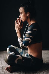 Side view of woman doing yoga while sitting at home