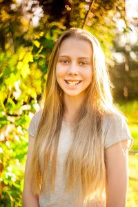 Portrait of smiling young woman against trees