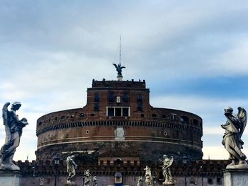 Low angle view of statue of building against cloudy sky