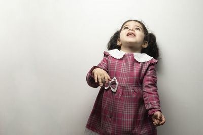 Girl looking away while standing against wall