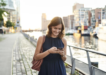 Germany, young woman with smart phone exploring hamburg