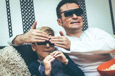 Young man holding sunglasses while sitting outdoors