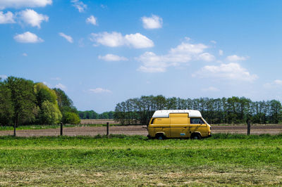 Van parked by field against sky