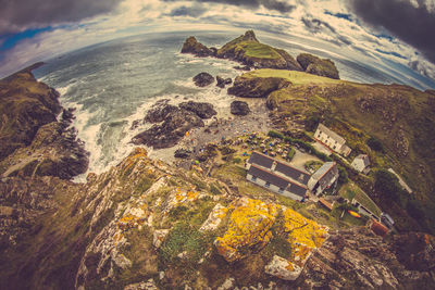 Scenic view of house on mountain by sea against sky