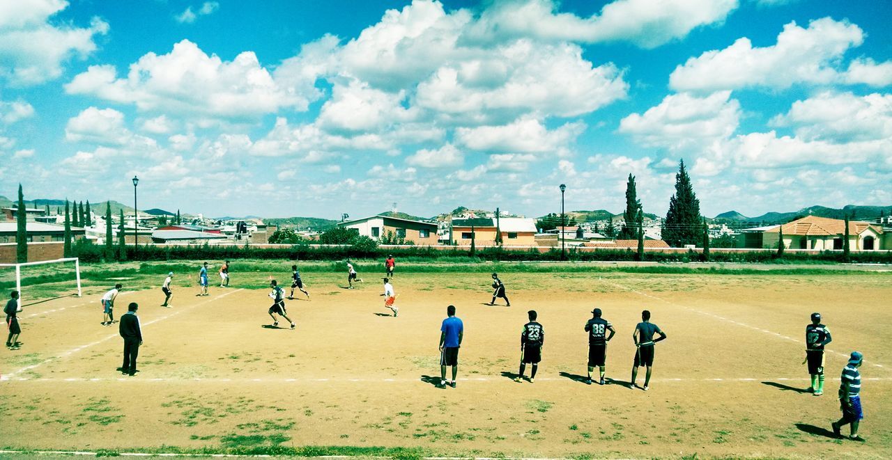 sky, lifestyles, men, cloud - sky, building exterior, built structure, architecture, person, leisure activity, large group of people, grass, cloud, walking, city, day, cloudy, tree, outdoors, sport