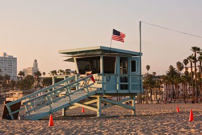 Flags on beach against buildings in city against clear sky