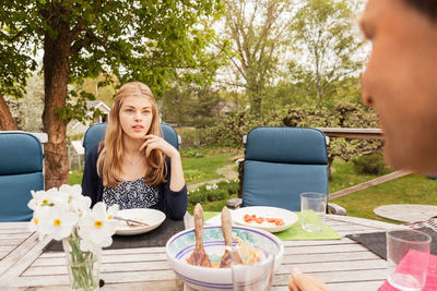 Teenage girl talking to father at table in yard