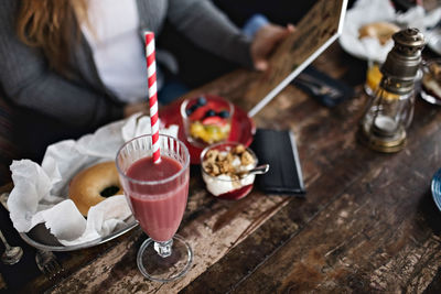 Midsection of woman holding menu while having brunch at dining table in restaurant