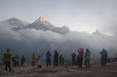 Tourists on field against mountains during winter