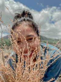 Close-up portrait of woman with plants on land against sky