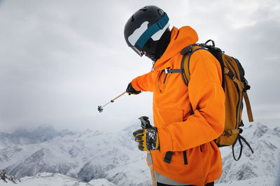 Portrait of a male skier at the top against the backdrop of epic mountains in the clouds. points