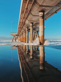 Pier on sea against clear blue sky