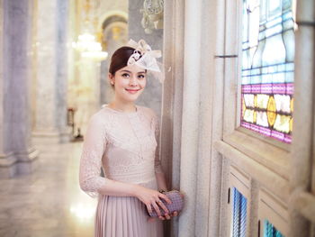 Portrait of smiling young woman standing by wall in church