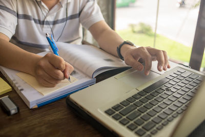 Midsection of man using laptop on table