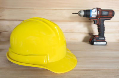 Close-up of yellow hardhat and power tool on table