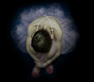 High angle view of ballet dancer sitting over black background