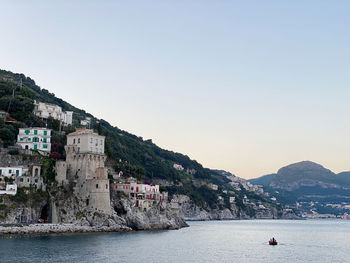 Buildings by sea against clear sky