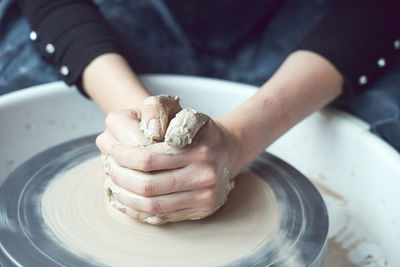 Midsection of woman making pottery in workshop