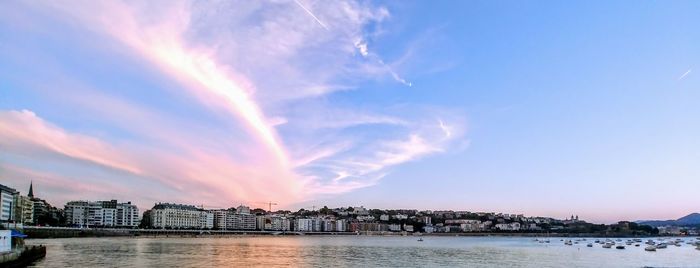 Scenic view of river by buildings against sky during sunset