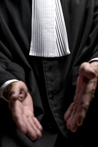 Midsection of lawyer gesturing against black background
