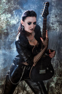 Portrait of young woman playing guitar