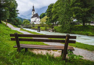 Bench in park by building against sky