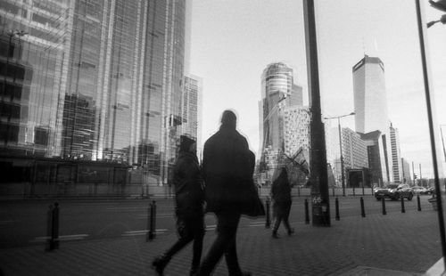 People walking on street against modern buildings in city