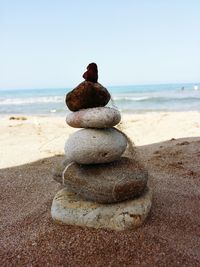 Close-up of stacked pebbles at beach against clear sky