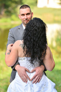 Portrait of groom making heart shape on bride back