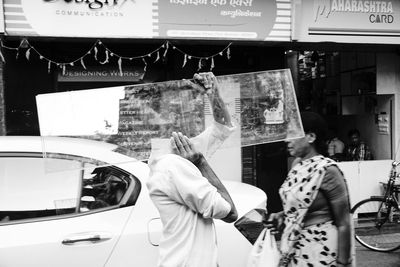 People standing by car on city street