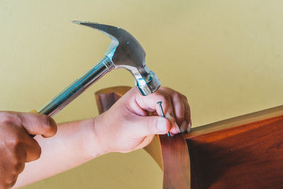 Cropped hand of carpenter fixing nail on wood