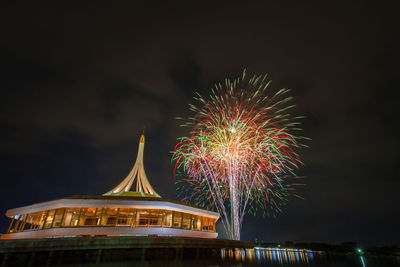 Firework display in city against sky at night