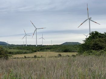 Wind turbines on field against sky