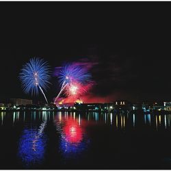 Firework display over river against sky at night