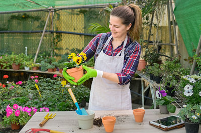 Happy female gardener admiring potted plant