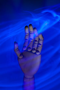 Close-up of human hand against blue background