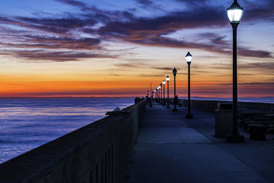 Street light by sea against sky during sunset