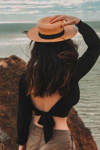 Rear view of woman wearing hat by sea