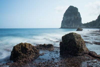 Rock formation on sea shore against sky