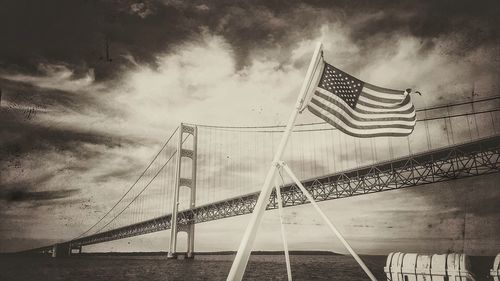 Low angle view of suspension bridge against cloudy sky