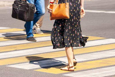 Low section of people walking on zebra crossing