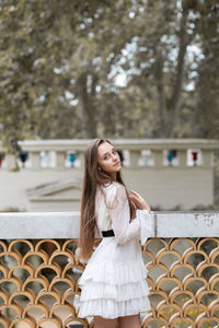 Portrait of a young woman standing against trees