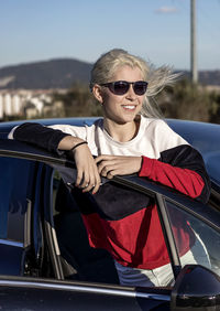 Young woman wearing glasses looking through car door