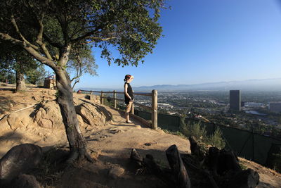 Side view of woman standing by railing against sky