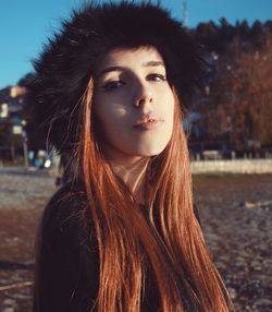 Close-up portrait of young woman standing against sky