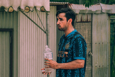 Side view of man standing against wall