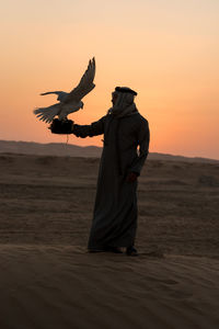 Rear view of woman standing against sky during sunset