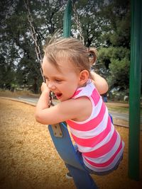 Playful girl swinging on swing at park