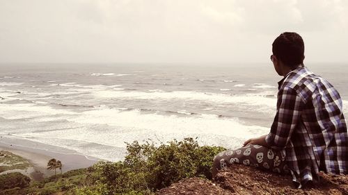 Side view of man looking at sea against sky