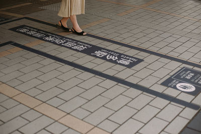 Low section of person with text on tiled floor at subway station